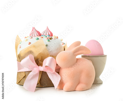 Tasty Easter cake, toy bunny and holder with egg on white background