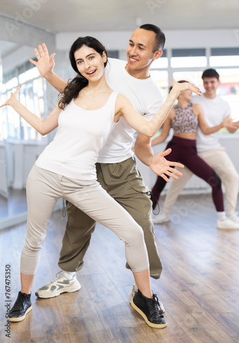 Group of young contemporary active people dancing twist or rock and roll dance in dance hall