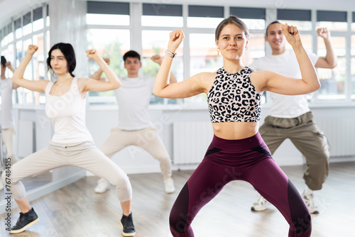 Group of young people, girls and guys in sportive casual style clothes dancing in choreography class photo