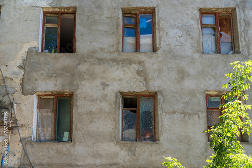 A building with four windows and a tree in front © Iurii Gagarin