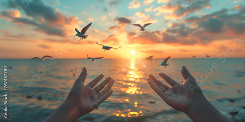Silhouette of human hands and flying seagulls on sunset background © Henryz