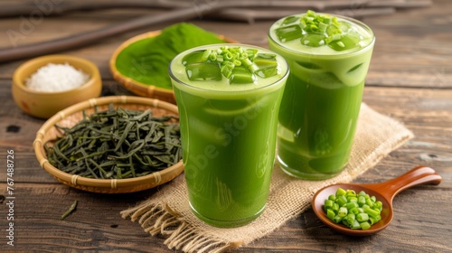  a couple of glasses filled with green liquid next to a bowl of green beans and a bowl of seaweed.