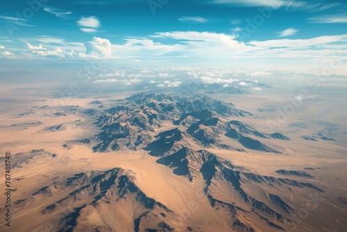 An aerial perspective showing a rugged mountain range cutting through the desert landscape.