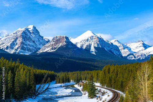 Canadian Rockies in the Winter at Morant's Curve in Banff National Park featuring Haddo Peak, Saddle Mountain, Fairview Mountain, Mount Whyte and Mount Niblock. Railway track winds through the valley.