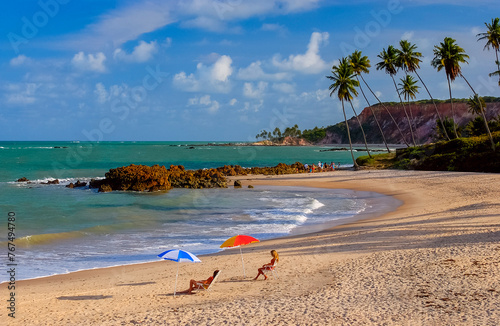 Tabatinga Beach, Conde, Paraiba, Brazil. Umbrellas with people on the beach on a sunny afternoon. photo