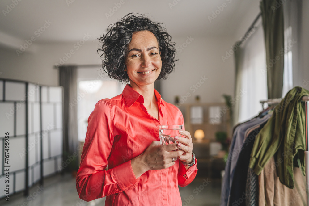 Portrait of one adult mature woman hold glass of water at home