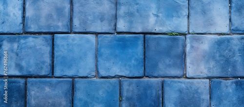 A close up of a symmetrical pattern of azure rectangular tiles on a wall. The electric blue tints create a mesmerizing effect, showcasing composite building materials