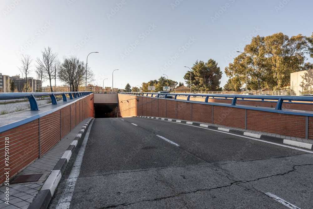 A road track with access to a tunnel in an area with blue railings on the walls