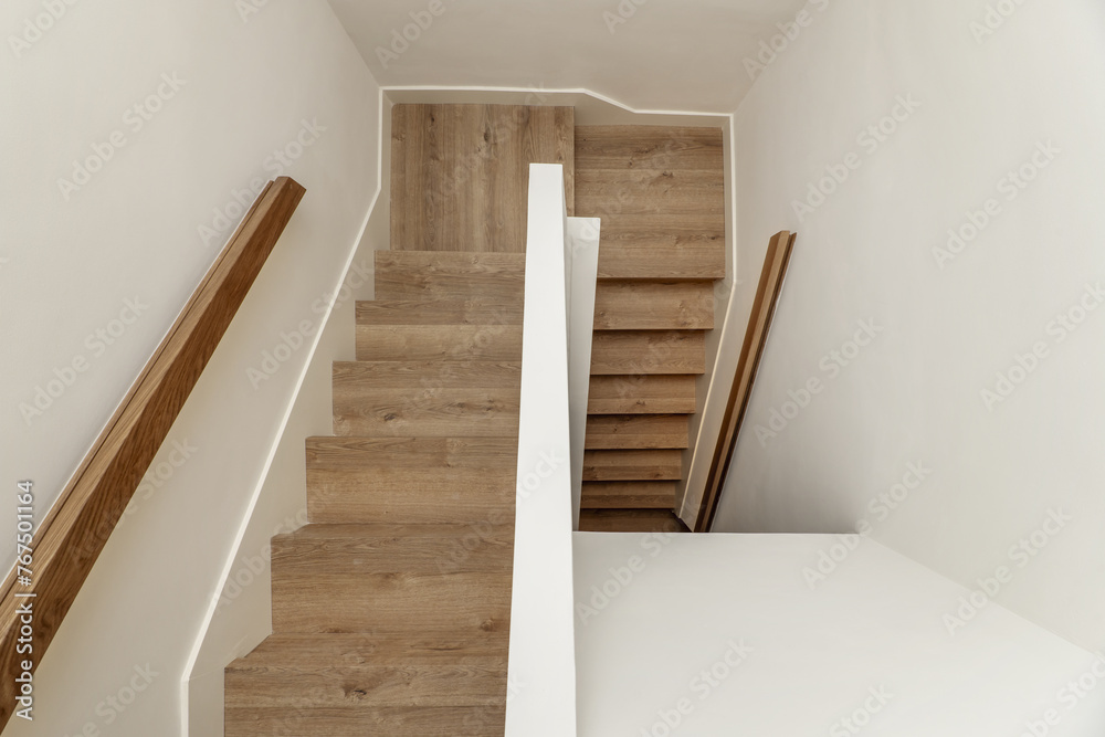 stairs with wooden steps and beech wood railings in the interior of a single-family residential home in a minimalist style stairs with wooden steps and beech wood railings in the interior of a single-family residential home in a minimalist style