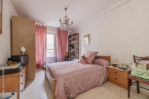 Bedroom with double bed with pale pink bedspread matching the window curtains