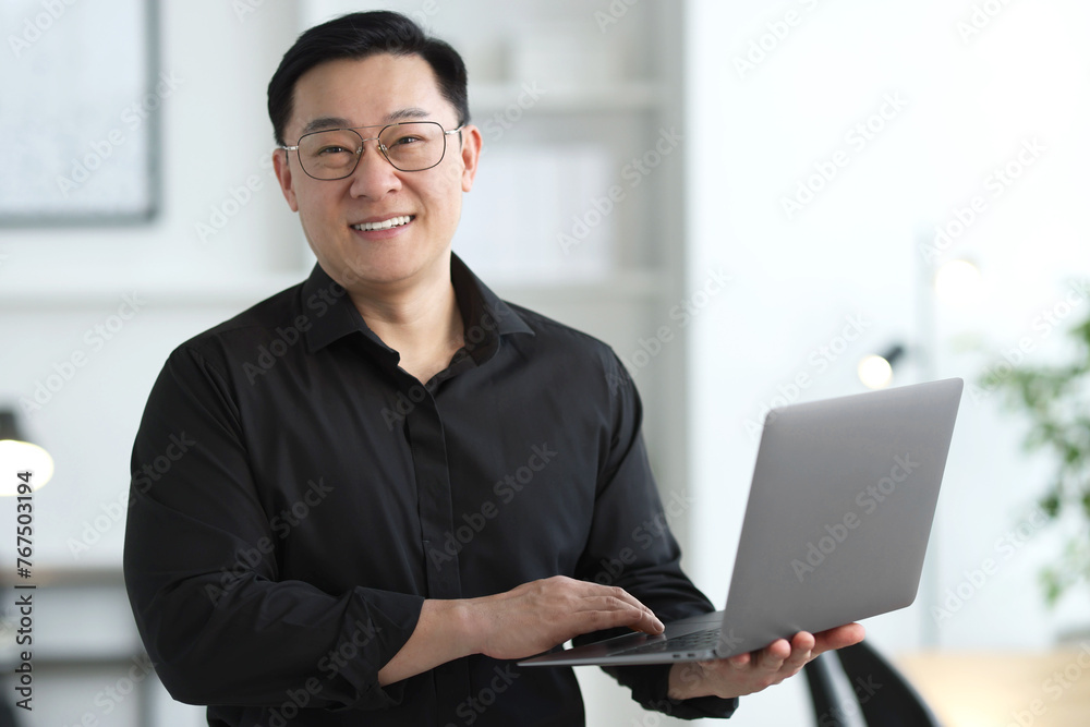 Portrait of smiling businessman with laptop in office Portrait of smiling businessman with laptop in office