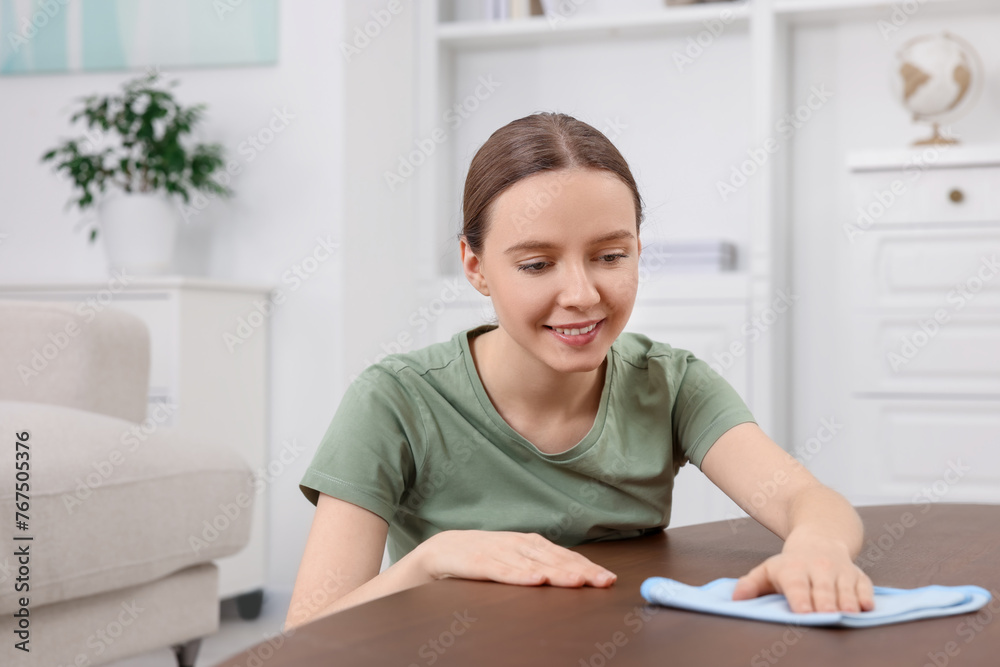 Woman with microfiber cloth cleaning wooden table in room Woman with microfiber cloth cleaning wooden table in room