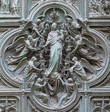 MILAN, ITALY - SEPTEMBER 16, 2024: The detail from main bronze gate of the Cathedral - Virgin Mary with the angels by Ludovico Pogliaghi (1906).