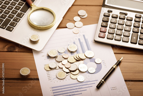 Data drawings, coins, laptops, calculators, and other office supplies placed on desks - Financial concepts