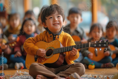 Cheerful child playing guitar in multietinic children's music class at school