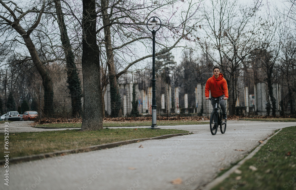 Casual young man cycling through a tranquil park, enjoying nature on an overcast day. Casual young man cycling through a tranquil park, enjoying nature on an overcast day.