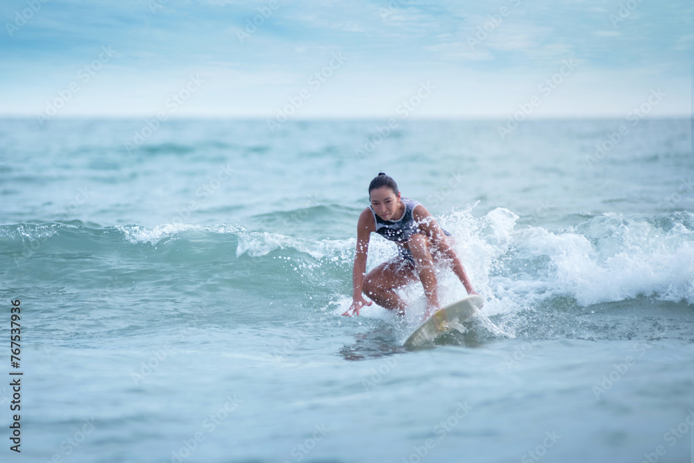 Asian surfing woman riding the waves on sunny day, outdoor activities, water sports activities concept