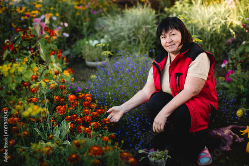 A woman poses in her flower garden.