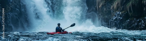 A kayaker paddles near a majestic waterfall