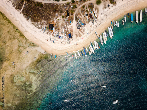 Aerial view of lines of wooden tourist boats on a sandy beach of a tropical island © whitcomberd