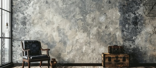 Photo of a loft interior mock up featuring a grey concrete textured wall, a black leather chair, and a vintage wooden trunk. The background photo includes space for adding text.