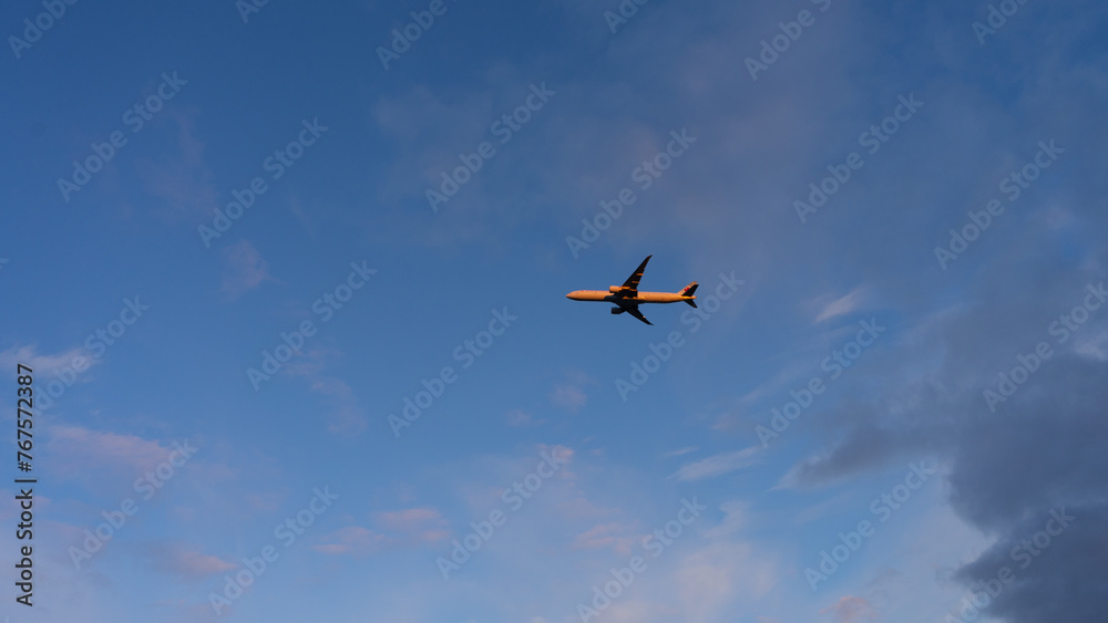 A plane flying in blue sky catching sunlight. A plane flying in blue sky catching sunlight.