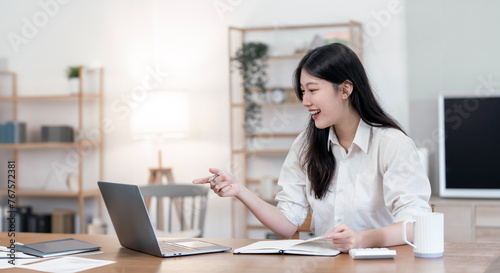 Beautiful business lady is looking at laptop screen and smiling while working in office