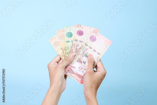 Woman hands holding Saudi Arabia money isolated on blue background photo