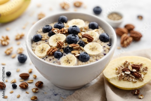 Oat porridge bowled on the table with banana, blueberries, walnuts, chia seeds and almond milk for a healthy breakfast, top view