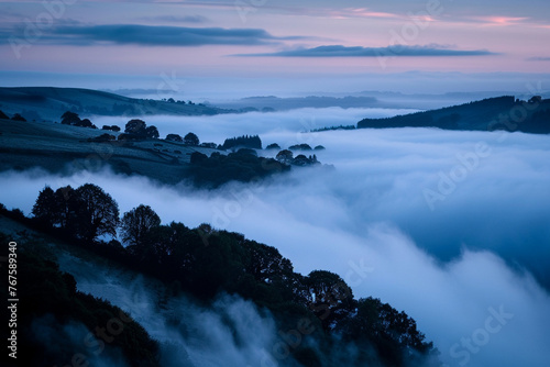 A dense fog rolling over a hilly landscape at dawn, with just the tops of trees peeking through the mist