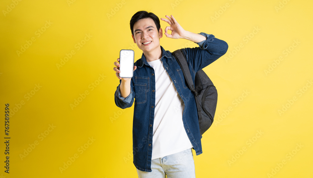 Portrait of Asian male student posing on yellow background Portrait of Asian male student posing on yellow background