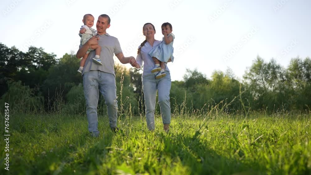 people in the park. happy family walking in the park with two baby toddlers in their arms. friendly family kid dream concept. parents and baby walk in nature relax in lifestyle summer people in the park. happy family walking in the park with two baby toddlers in their arms. friendly family kid dream concept. parents and baby walk in nature relax in lifestyle summer
