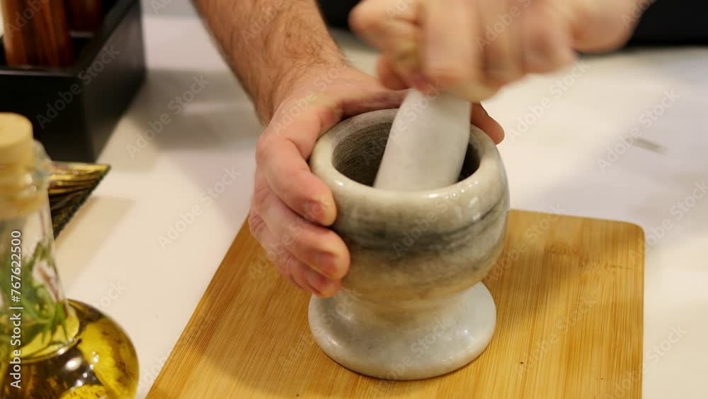 A man grinds spices in a mortar and pestle. The mortar and pestle are essential tools for crushing spices into fine powders. The mortar is made of solid stone, providing a sturdy base for grinding.