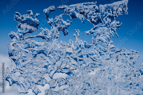 Cracks surface of the frozen lake of Baikal lake in winter season. ice texture cracks baikal, abstract background winter ice transparent blue. Selective focus. © Nikita