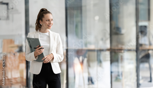 Modern business woman holding file folder standing in the office with copy space