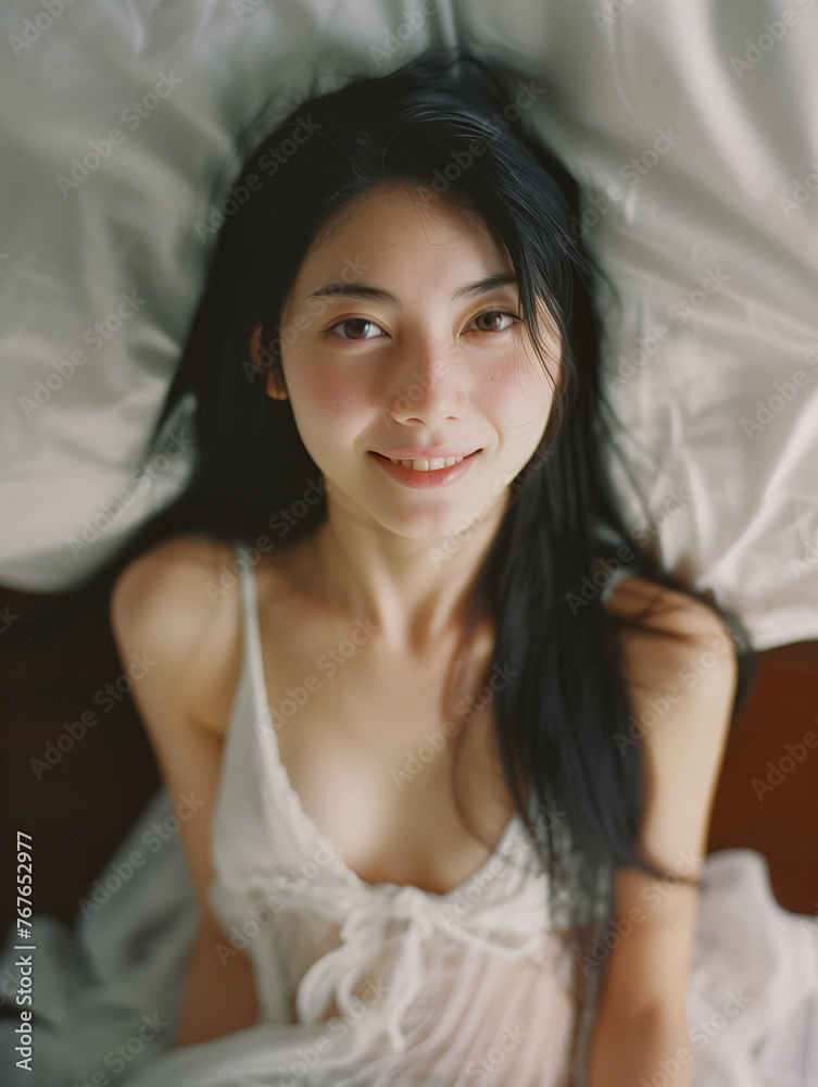 smiling attractive eurasian woman lying on bed from above wearing slinky white chemise smiling attractive eurasian woman lying on bed from above wearing slinky white chemise