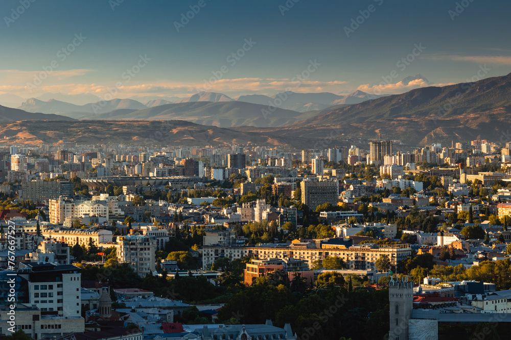 Obraz premium View of Tbilisi from the surrounding hills. In the background you can see the Caucasus Mountains. A warm autumn day in the capital of Georgia.