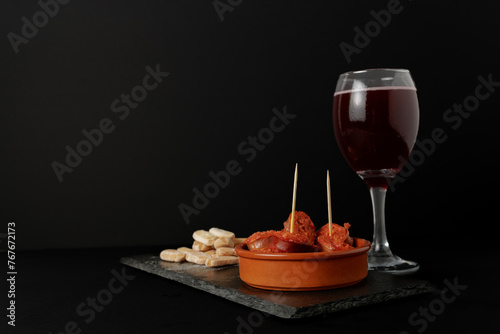 chorizo frito ,typical spanish tapa in a clay pot accompanied by bread and a glass of red wine.