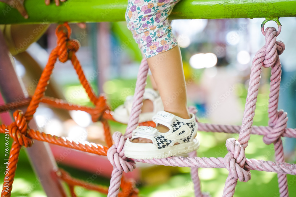 Foot on rope and climbing up high on the rope net or spider web at outdoor playground, entertainment and recreation for children, mountaineering training.