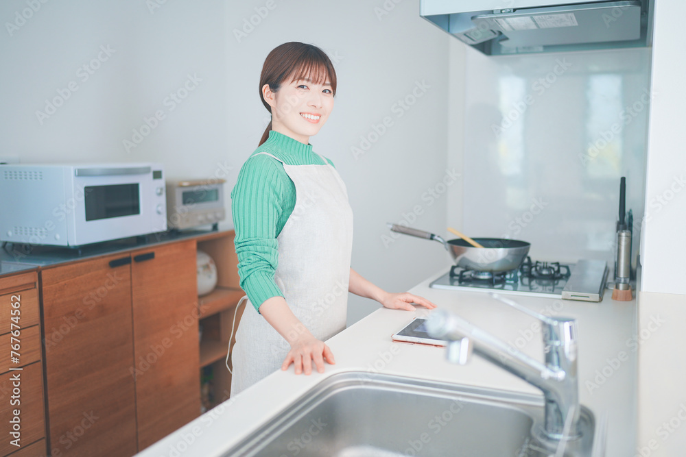 キッチンカウンターでタブレットを使ってレシピを考える女性 キッチンカウンターでタブレットを使ってレシピを考える女性