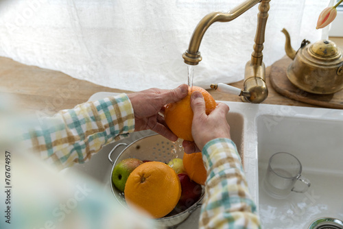 elderly man hands wash fruits by water in kitchen photo