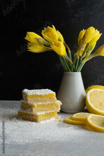 Still life with lemons, lemon bar squares, and yellow daffodils. photo