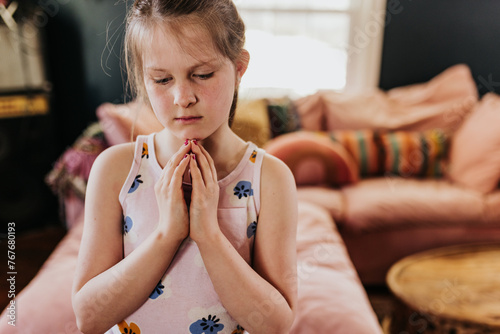 close up of young girl meditating in tree pose in living room photo