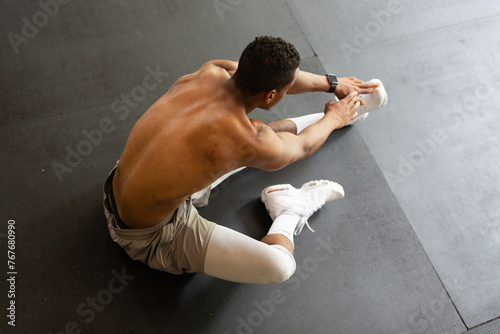 Fit Shirtless Man Stretching on Gym Floor photo