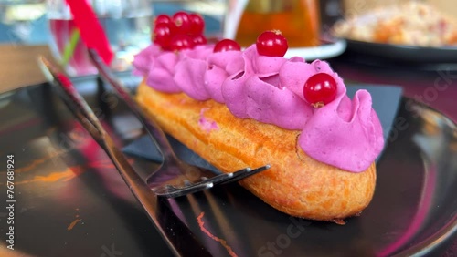 Delicious eclair with forest berry cream on a plate at a bakery, choux dough pastry filled with purple cream, sweet dessert, 4K shot photo