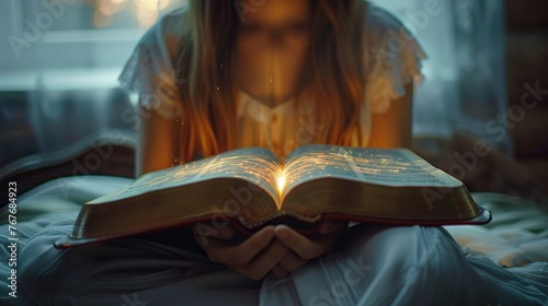 A woman is holding an open book with a light shining through it. The light is glowing and illuminating the pages of the book. Concept of wonder and curiosity