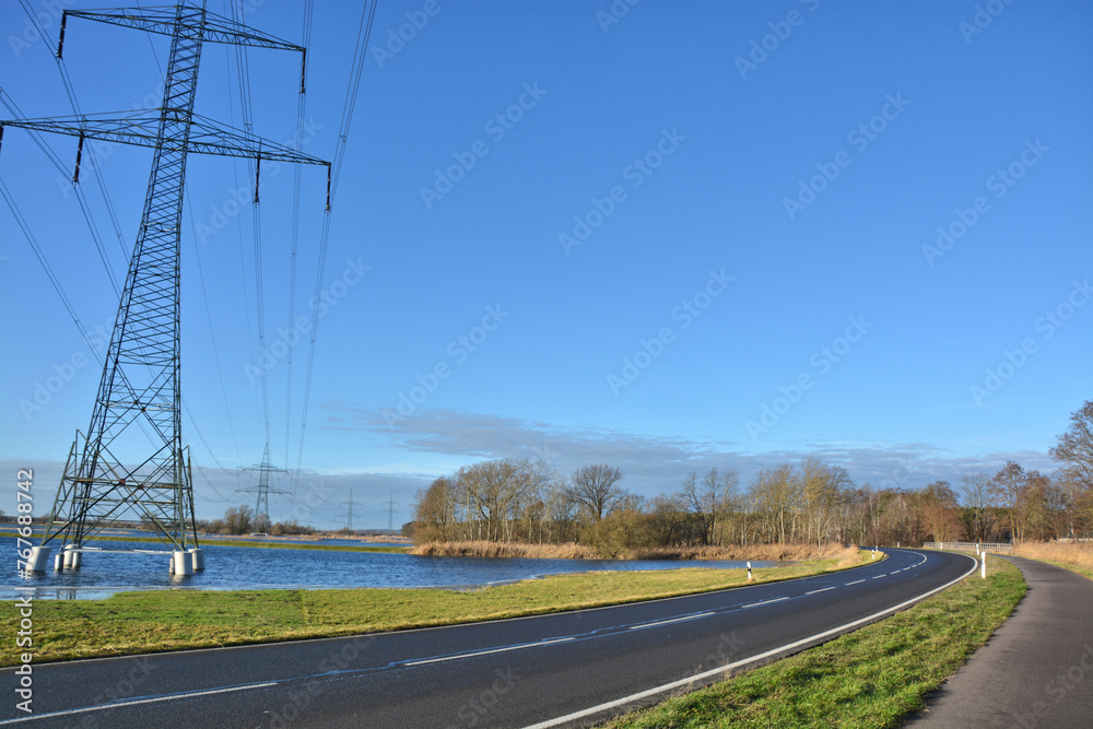 Strommast auf überschwemmter Wiese an einer Strasse Strommast auf überschwemmter Wiese an einer Strasse