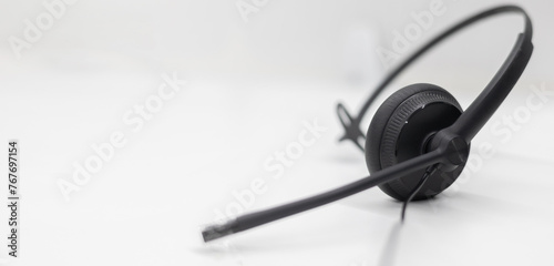 close up black headset on the white table background in 24/7 operation room to communicate with provider or response client for call center and hotline service concept