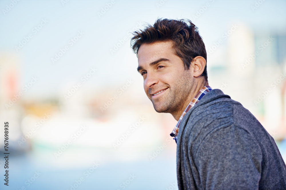 Fototapeta premium Man, smile and mockup for outdoor and trip for travel or walk in urban or city with joy. Young person with joy and jacket and looking for view, comfort and relax for break and isolated aesthetic