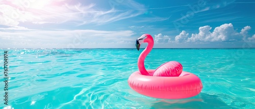 A pink flamingo float is floating in the ocean. The scene is bright and cheerful, with the pink flamingo adding a pop of color to the blue water. Concept of relaxation and leisure photo